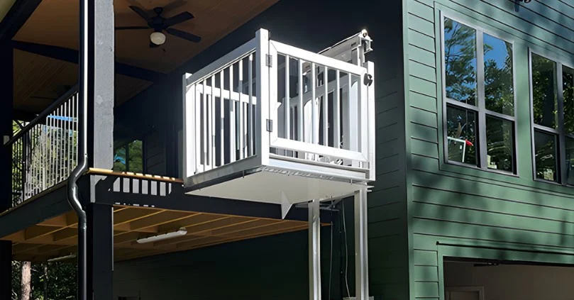 Affordable Elevator Website – Homepage Lifestyle hero White home elevator attached to a modern green house exterior, connected to an elevated deck with black railing.