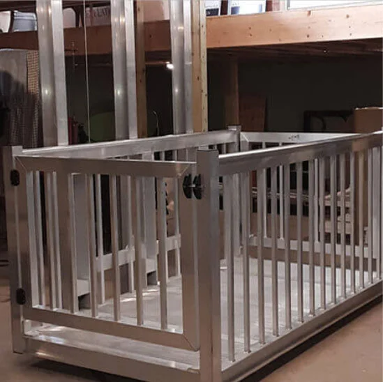 Sturdy metal frame of a home elevator under construction, featuring vertical bars and a gate, set in a workshop.